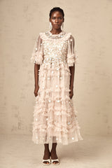 A woman wearing a midi dress with floral embroidery and tiered ruffles