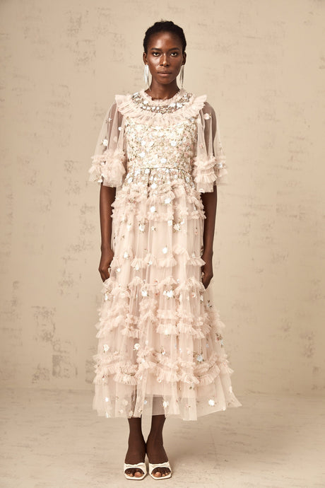 A woman wearing a midi dress with floral embroidery and tiered ruffles