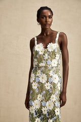 A woman wearing a midi length dress with floral embroidery and hollow carved details standing in a relaxed pose