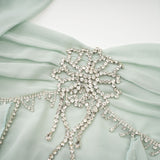 A woman wearing a midi length dress with ruffled details and embellishments named Salilah The dress features a fitted bodice and flowy skirt
