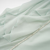 A woman wearing a midilength dress with ruffled details and embellishments named Salilah