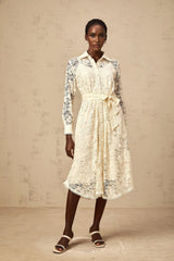 A woman wearing a neutralcolored midi shirt dress with guipure lace detailing standing in a casual pose