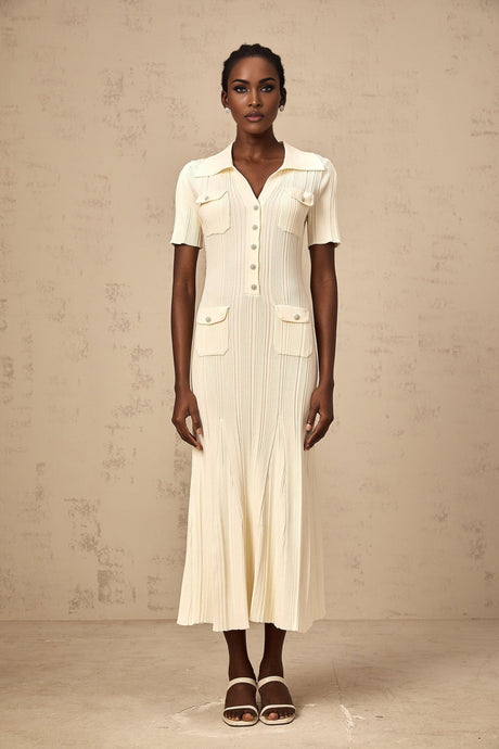 A woman wearing a neutralcolored ribbed knit midi dress with a formfitting silhouette and long sleeves standing in a relaxed pose