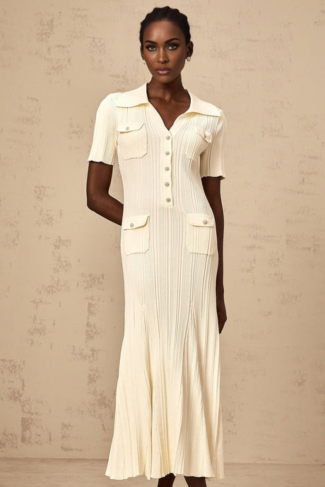 A woman wearing a neutralcolored ribbed knit midi dress with long sleeves standing against a plain background