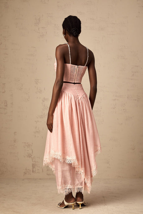 A woman wearing a pink matching set consisting of an asymmetric ruffled top and skirt The top has one shoulder and the skirt features a ruffle detail The outfit is vibrant and feminine