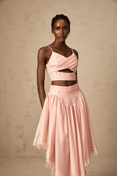 A woman wearing a pink matching set consisting of an asymmetric ruffled top and skirt The top has one shoulder and the skirt features ruffles The outfit is called Tamara and has a feminine and stylish appearance