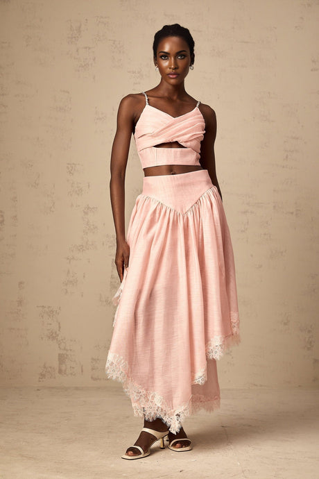 A woman wearing a pink twopiece outfit consisting of an asymmetric ruffled top and matching skirt The top has one shoulder and cascading ruffles while the skirt features a flattering fit The set is vibrant and feminine in appearance