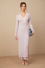 A woman wearing a pleated knit midi dress with a V neckline in a soft color standing in a relaxed pose