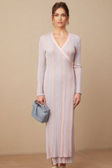 A woman wearing a pleated knit midi dress with a Vneck in a soft color standing against a plain background