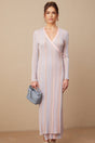 A woman wearing a pleated knit midi dress with a Vneck in a soft color standing against a plain background