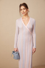 A woman wearing a pleated knit midi dress with a Vneck in a soft color standing in a relaxed pose against a plain background