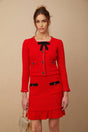 A woman wearing a red braided waffle knit jacket paired with a matching skirt forming a coordinated outfit set