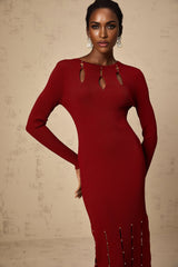 A woman wearing a red knit midi dress with long sleeves beaded details and cutout sections