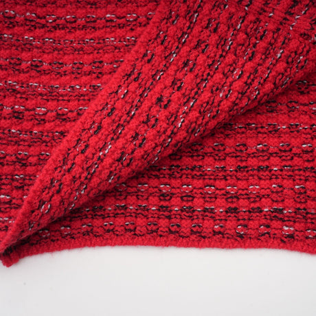 A woman wearing a red knitted midi dress with embellishments standing in a neutral background
