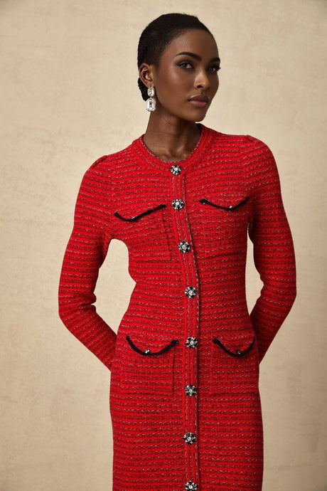 A woman wearing a red knitted midi dress with embellishments standing in a relaxed pose