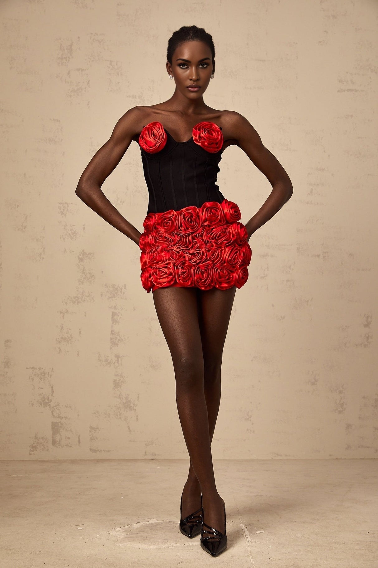 A woman wearing a red matching set consisting of a top and skirt adorned with rose appliques