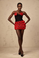 A woman wearing a red matching set consisting of a top and skirt adorned with rose appliques