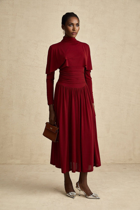 A woman wearing a red midi dress with ruched details and a flap design across the bodice