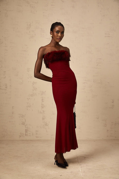 A woman wearing a red offshoulder midi dress with faux fur trim and mesh details