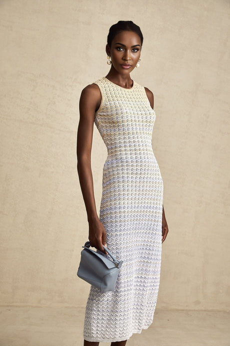 A woman wearing a ribbed knitted midi dress with contrasting colors named Pauline the dress features a fitted silhouette and extends to mid calf length