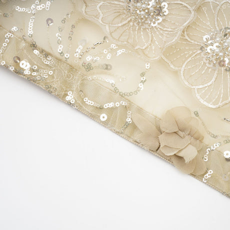 A woman wearing a sheer floral jacket with beaded embellishments and delicate organza fabric in a light luxurious style