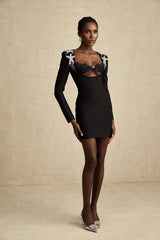 A woman wearing a short black dress with a sequined bustier top and a fitted silhouette