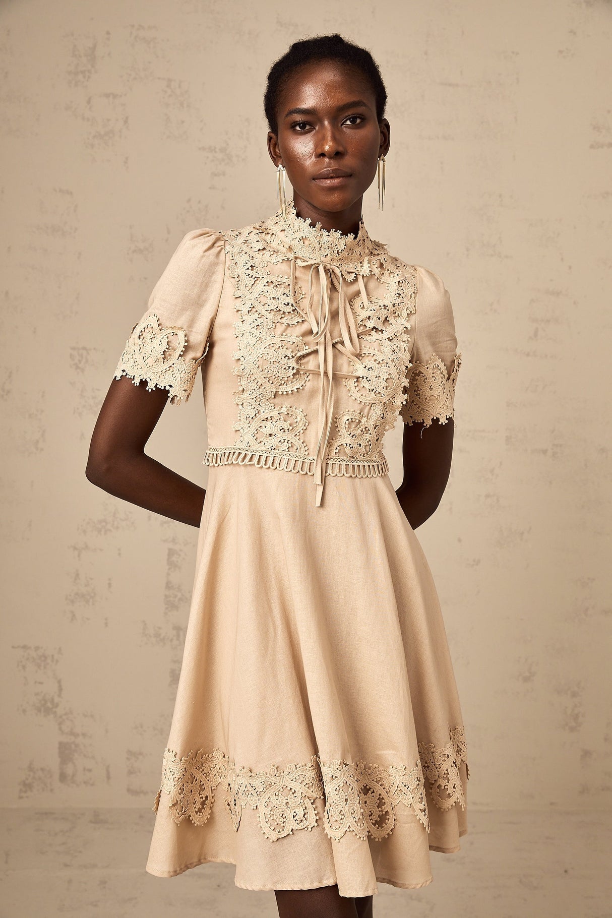 A woman wearing a short flared mini dress with corded lace detailing and a feminine silhouette