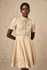 A woman wearing a short flared mini dress with corded lace detailing and a feminine silhouette