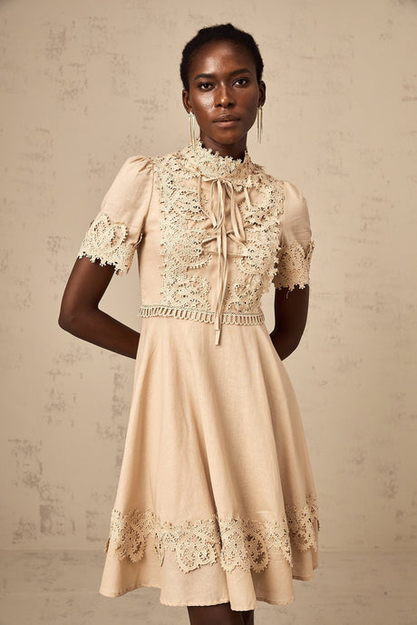 A woman wearing a short flared mini dress with corded lace detailing and a feminine silhouette