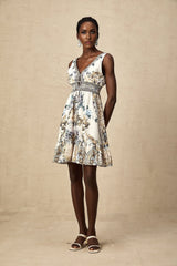 A woman wearing a short floral print dress with a vneck neckline The dress features a vibrant pattern and falls above the knee