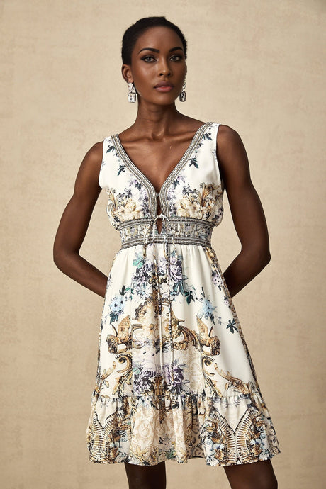 A woman wearing a short floral print dress with a vneckline and short sleeves standing against a light background