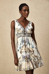 A woman wearing a short floral print dress with a vneckline and short sleeves standing against a plain background