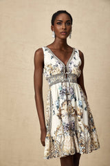 A woman wearing a short floral print dress with a vneckline standing against a plain background