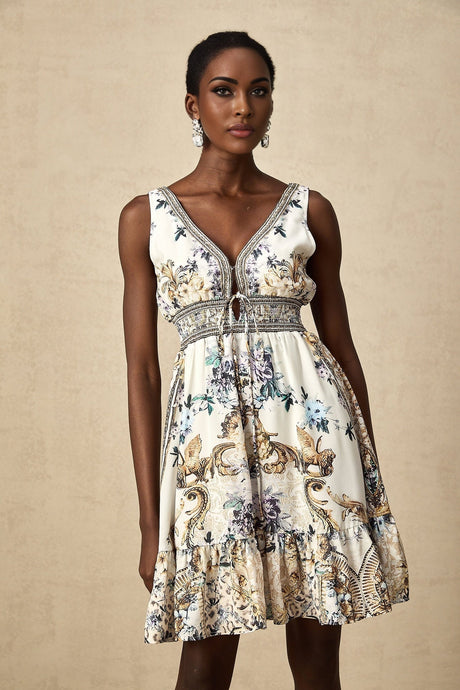 A woman wearing a short floral print dress with a vneckline standing in a casual pose against a plain background