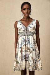 A woman wearing a short floral print dress with a vneckline standing in a casual pose against a plain background