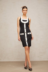 A woman wearing a short halterneck knit dress with color blocks in contrasting shades The dress features a fitted silhouette and falls above the knee