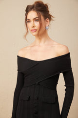 A woman wearing a short offshoulder dress in a ribbed knit fabric standing in a relaxed pose