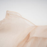 A woman wearing a short offshoulder dress with ruched detailing and layered fabric The dress has selftie straps and falls above the knee The model is posing to showcase the dress design