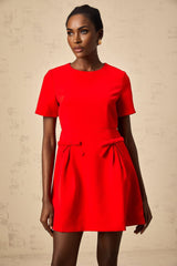 A woman wearing a short red mini dress with short sleeves and a decorative bow detail