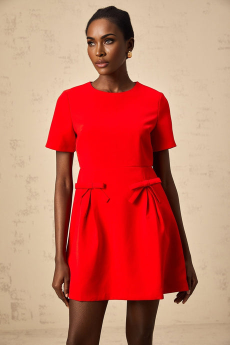 A woman wearing a short red mini dress with short sleeves and a decorative bow detail