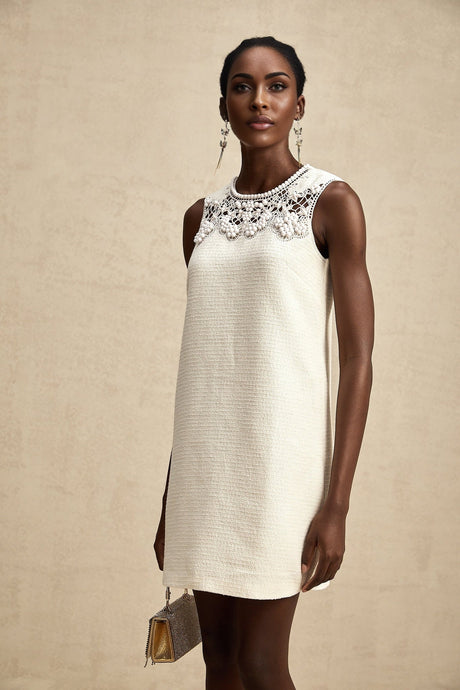 A woman wearing a short tweed dress with embroidery details and cutout sections