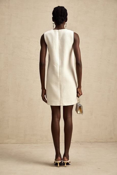 A woman wearing a short tweed dress with embroidery details and cutout sections