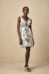 A woman wearing a short vneck dress with a vibrant floral print pattern standing against a plain background