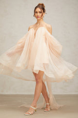A woman wearing a short voluminous mini dress with a large bow detail at the neckline
