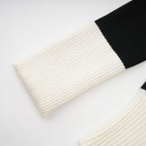 A woman wearing a short wool dress with colorblocked panels and ribbed knit texture The dress has long sleeves and a mini length silhouette showcasing contrasting colors in a geometric pattern