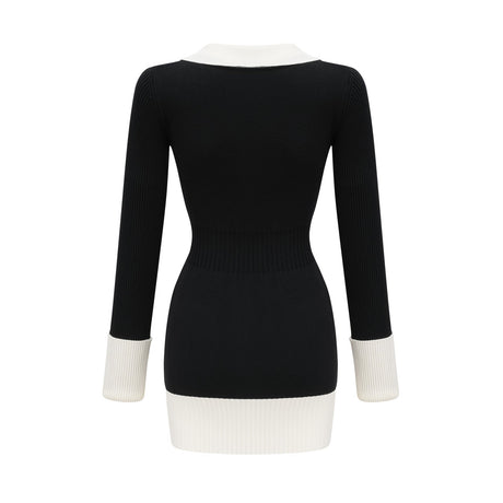 A woman wearing a short wool dress with ribbed knit texture featuring color block design in contrasting shades standing against a plain background