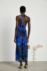 A woman wearing a sleek silk jumpsuit with a halter neckline in a soft flowing fabric The jumpsuit has a fitted bodice and wide leg pants creating an elegant silhouette