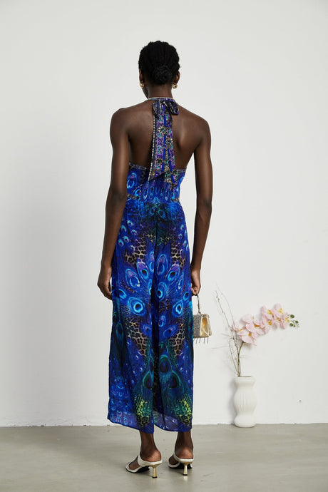 A woman wearing a sleek silk jumpsuit with a halter neckline in a soft flowing fabric The jumpsuit has a fitted bodice and wide leg pants creating an elegant silhouette