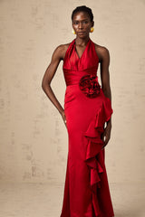 A woman wearing a vibrant red halterneck maxi dress with ruffled 3D petal details cascading down the length of the gown