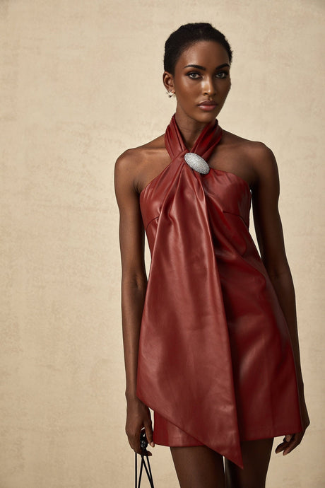 A woman wearing a vibrant red halterneck mini dress made of sheepskin The dress has a fitted silhouette and ends above the knee showcasing a stylish and bold look